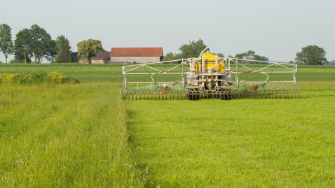 Ein Schlepper düngt auf einer grünen Wiese