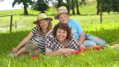 Eine Mutter mit ihren zwei Kindern auf einer saftgrünen Wiese