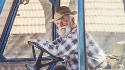 Ein alter Rentner sitzt im Traktor