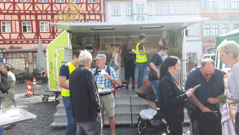 Menschen auf dem Marktplatz vor dem Schweinemobil