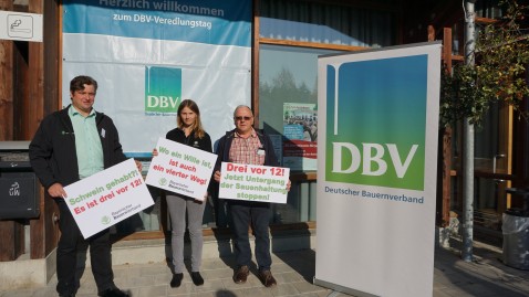 Drei Personen mit Plakaten demonstrieren