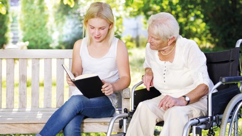 Frühzeitig an das Alter denken - eine junge Frau liest einer Seniorin etwas vor. 