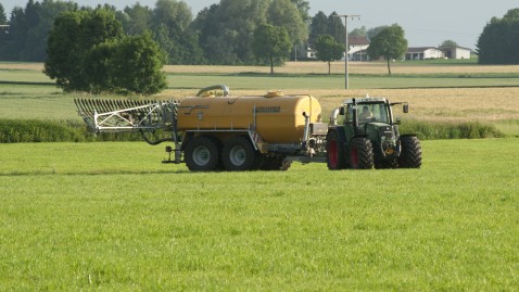 Ein Landwirt bringt Gülle auf seiner Wiese aus. 