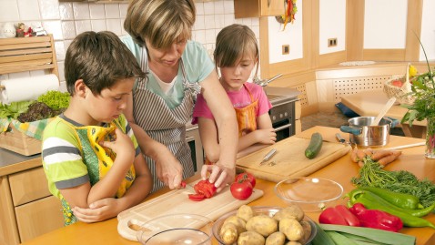 Eine Frau hilft Kindern bei der Zubereitung von frischen Lebensmitteln