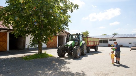 Eine Hofstelle mit Traktor und Menschen in der Mitte