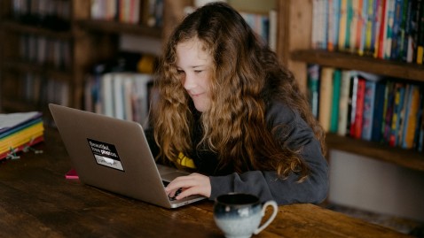 Ein junges Mädchen lernt daheim am Macbook
