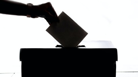 Hand steckt Umschlag in wahlurne