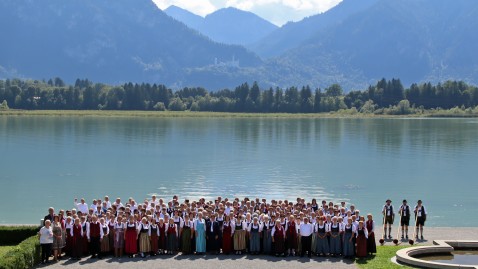 250 Chorsängerinnen und Sänger beim Gruppenbild vor dem Forggensee mit Alpenpanorama und dem Schloss Neuschwanstein im Hintergrund