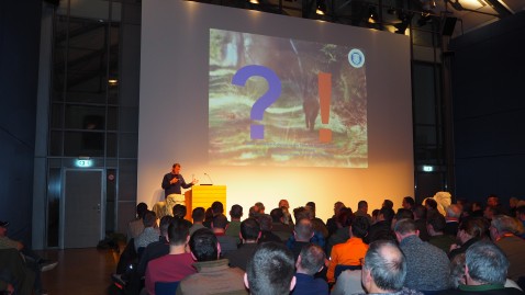 Dr. Keuling auf der Bühne beim Vortrag im vollbesetzten Saal