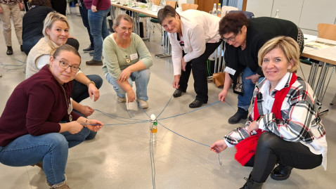 Ein gekochtes Ei sollte mithilfe von Schnüren und einem Ring gemeinsam auf einen Flaschenhals gesetzt werden – ein Sinnbild dafür, dass alle „an einem Strang ziehen“, auch wenn jede Position eine andere ist