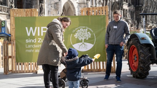 Ein kleines Kind freut sich über den alten Bulldog, den der Herrschinger Grundkurs auf den Marienplatz gebracht hat