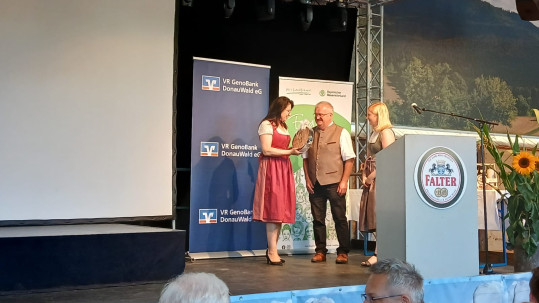Kreisobmann Roland Graf und die stellvertretende Kreisobfrau Teresa Fenzl überreichten Martina Englhardt-Kopf eine handgefertigte Holzuhr aus der Region.