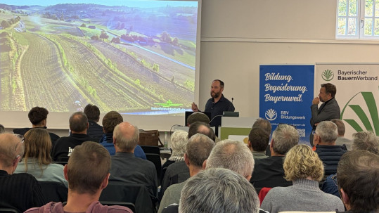 Dr. Philipp Gerhardt, Baumfeldwirtschaft Deutsche Agroforst GmbH (Mitte, stehen), erläuterte, wie landwirtschaftliche Wässersysteme geplant und umgesetzt werden können, damit sie Extremwetterereignisse wie etwa Trockenperioden oder Starkregen abpuffern. Im Bild Thomas Keller, Leiter des Wasserwirtschaftsamts Ansbach (rechts, stehend), das Partner der gastgebenden Initiative Heimat.Boden.Wasser des Bodenschutztages ist.